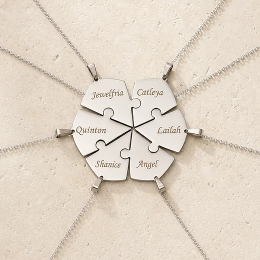 Engraved interlocking heart puzzle necklace arranged on an ivory surface