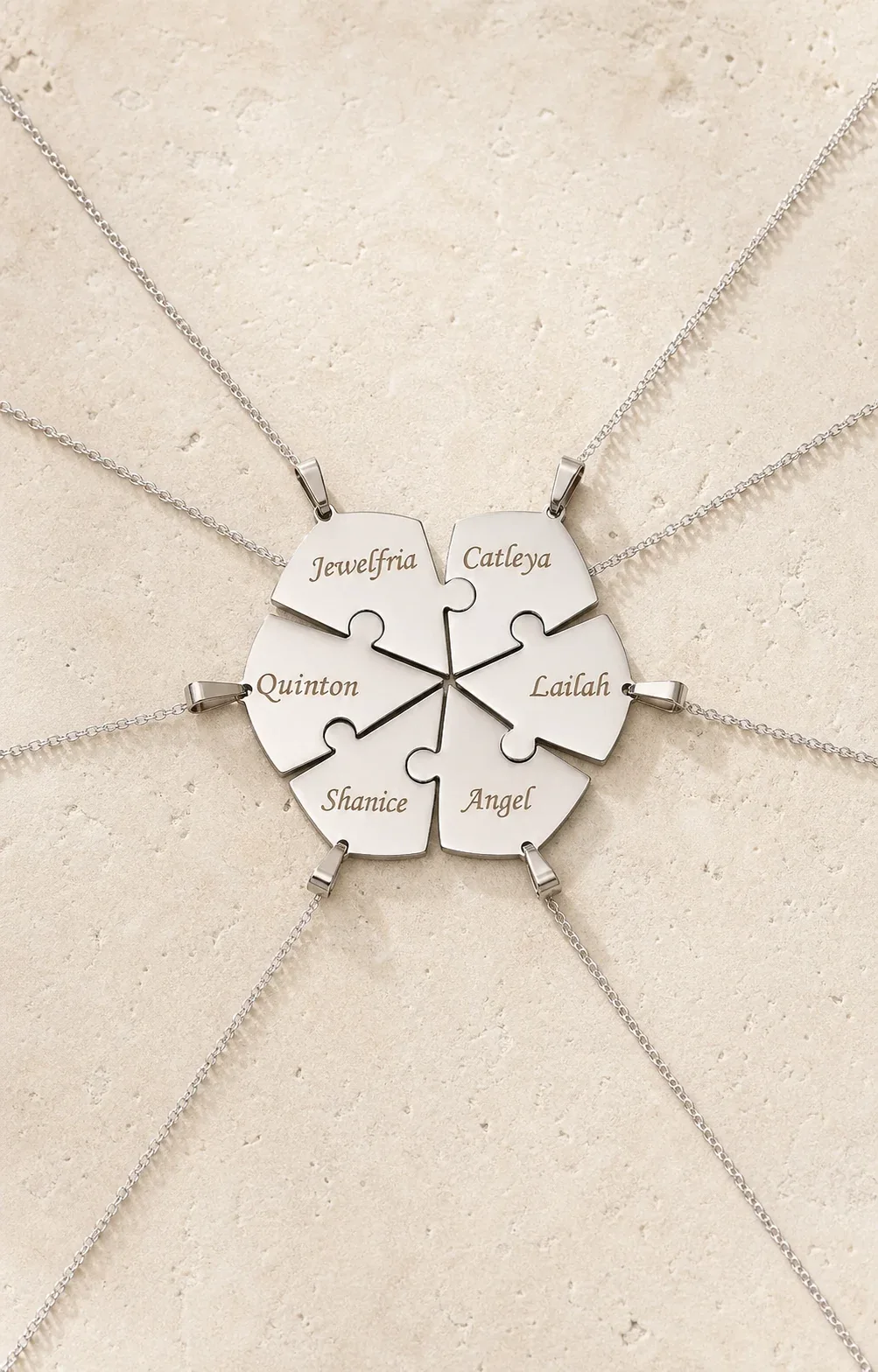 Engraved interlocking heart puzzle necklace arranged on an ivory surface
