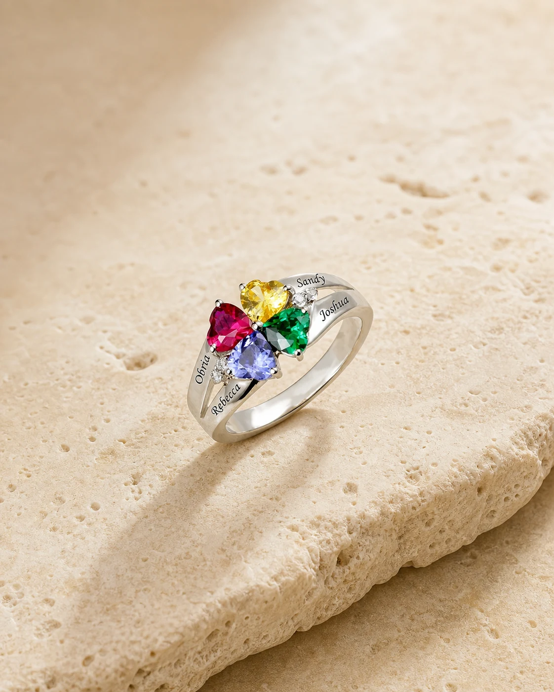 Engraved family birthstone ring photographed on an ivory stone surface