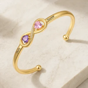 Gold tone open-heart cuff with two engraved names and two birthstones