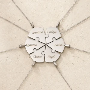 Engraved interlocking heart puzzle necklace arranged on an ivory surface