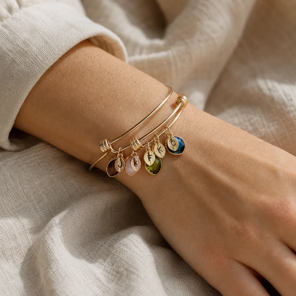 Family branch bangle showing engraved leaf charms and small colored birthstone accents