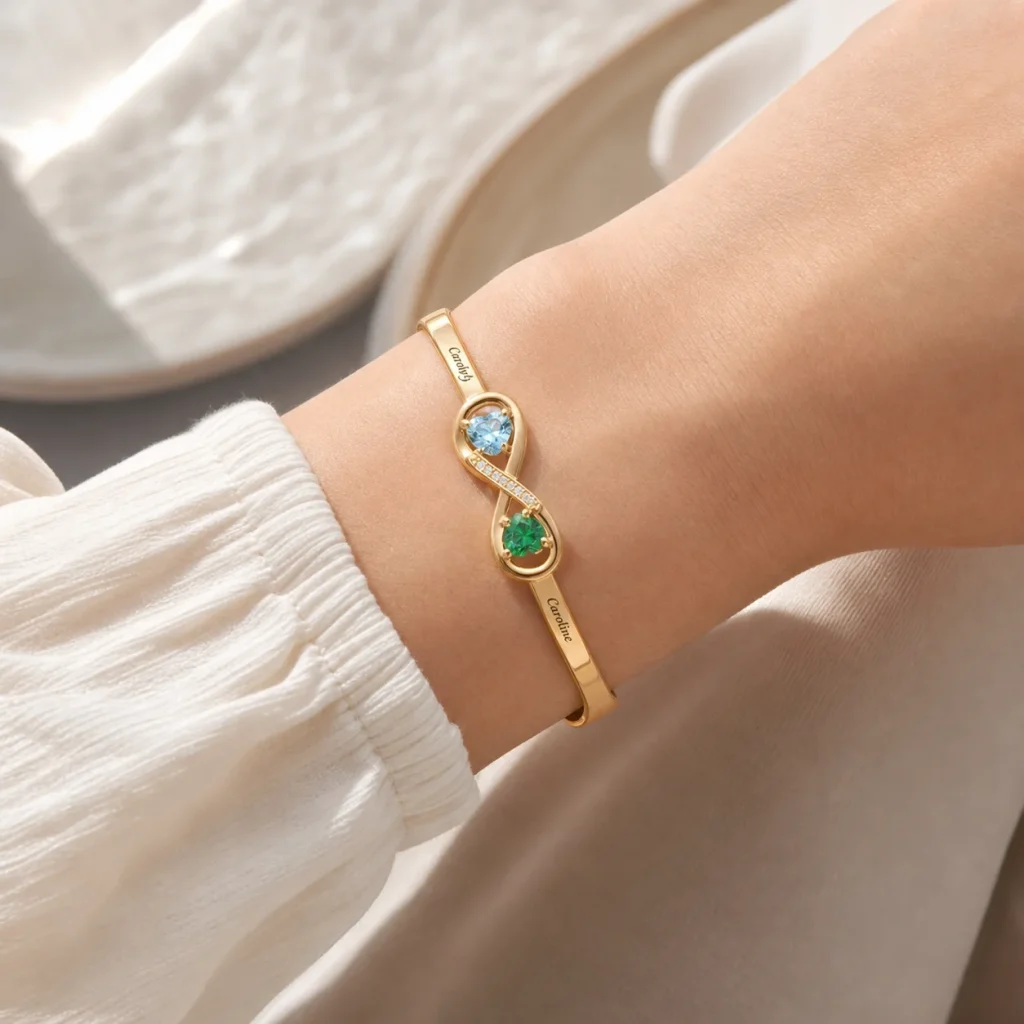 Open heart plated cuff with two engraved names and simulated birthstone accents shown on a wrist
