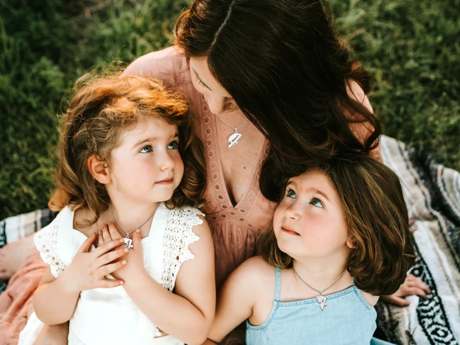 Editorial outdoor family scene with a mother and two children wearing separate heart necklaces