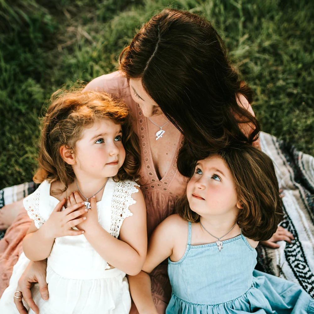 Editorial outdoor family scene with a mother and two children wearing separate heart necklaces
